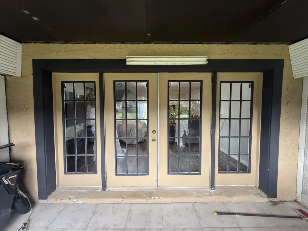 Old dark-framed French doors and sidelites before replacement