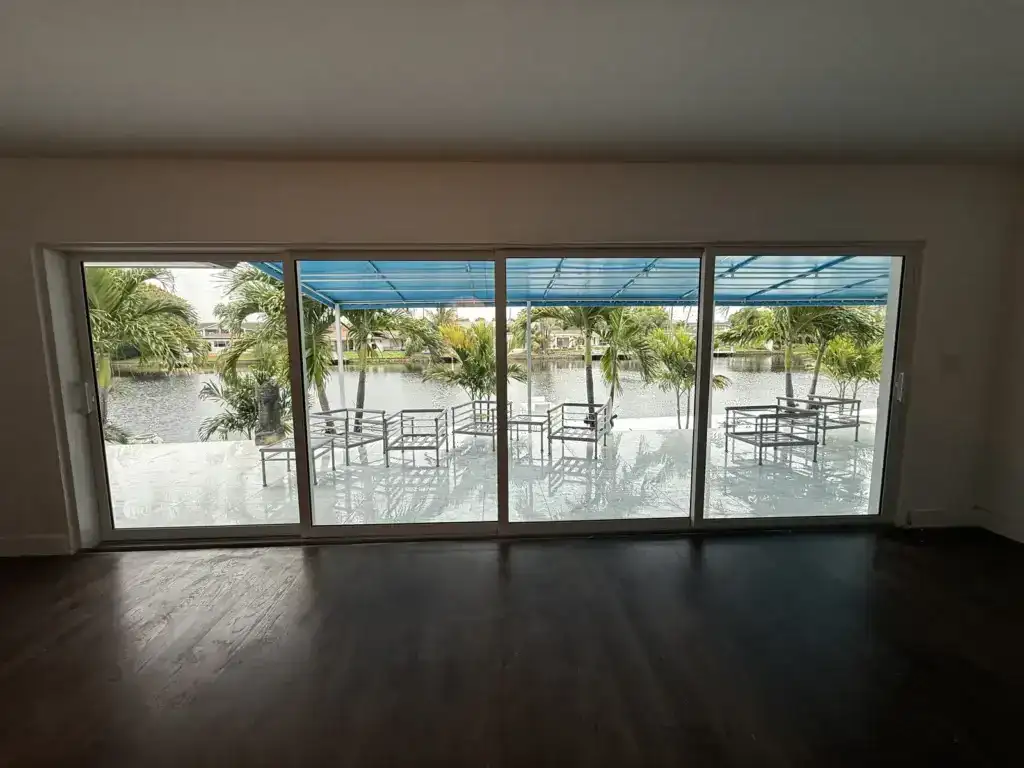Four-panel impact sliding glass doors installed in an enlarged opening facing a canal in South Florida