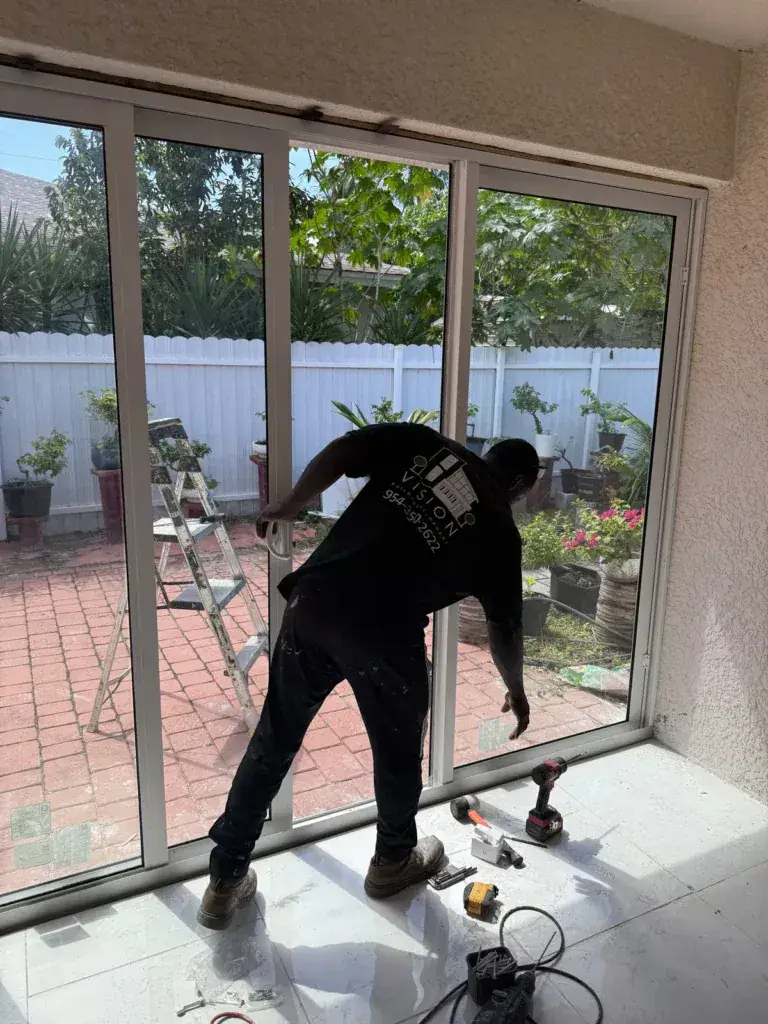 Installer securing an impact glass panel during a patio enclosure