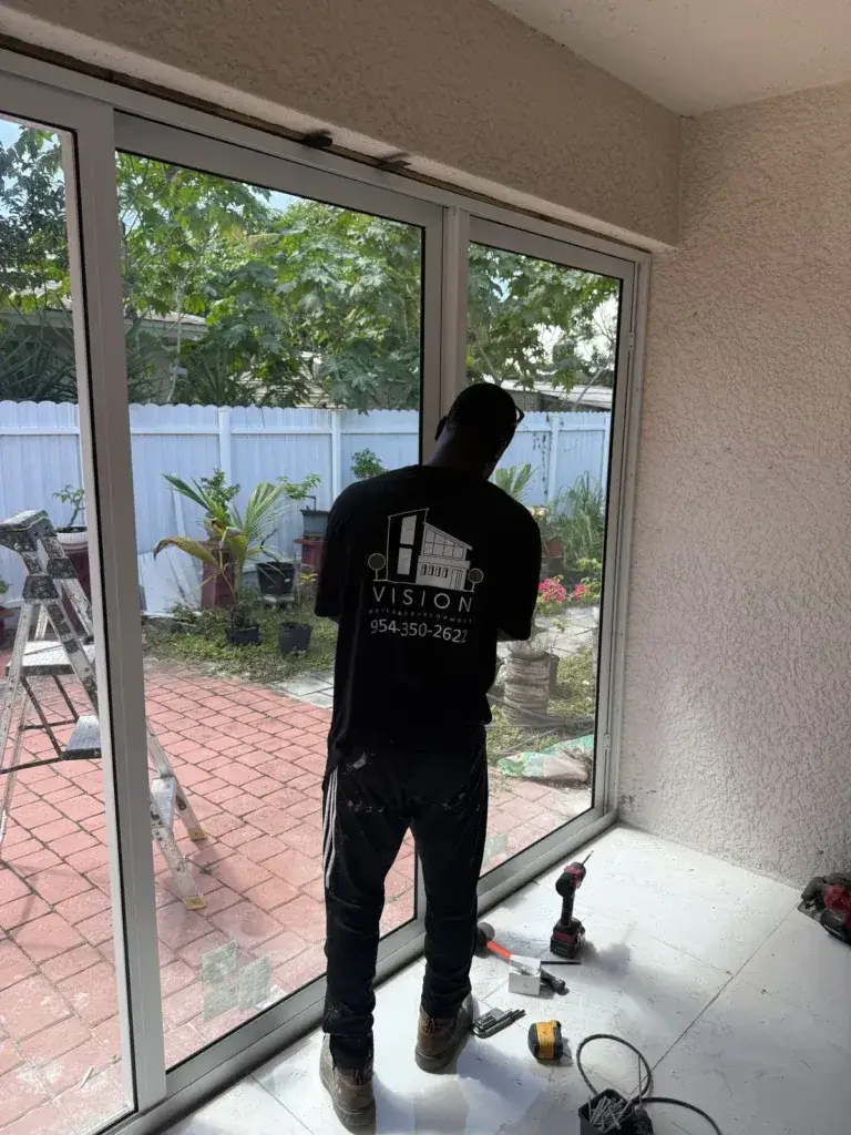 Vision Aluminum & Glass installer setting floor-to-ceiling impact glass panels to enclose a patio