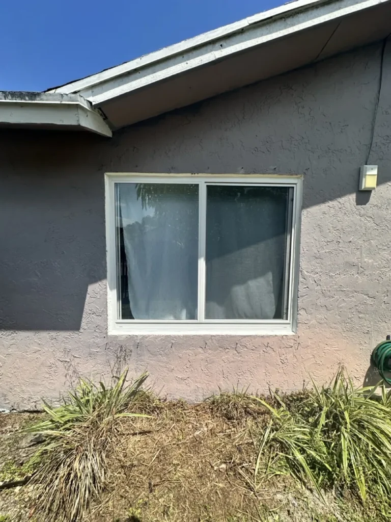New white impact horizontal-roller window on a stucco wall