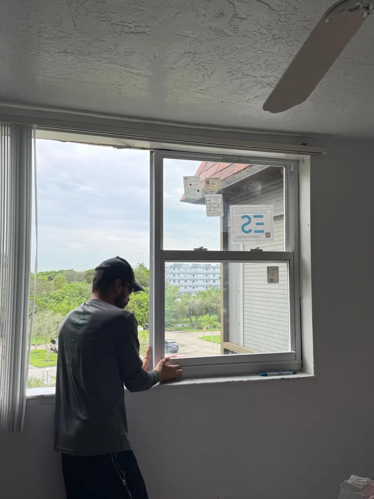 Installer fitting a new impact window in a bedroom in Plantation, FL