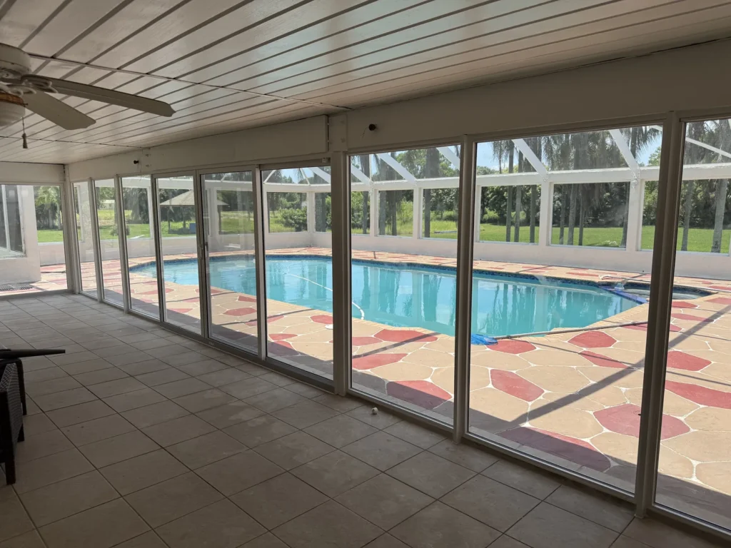 Pool room enclosed with impact glass walls, view across the pool deck