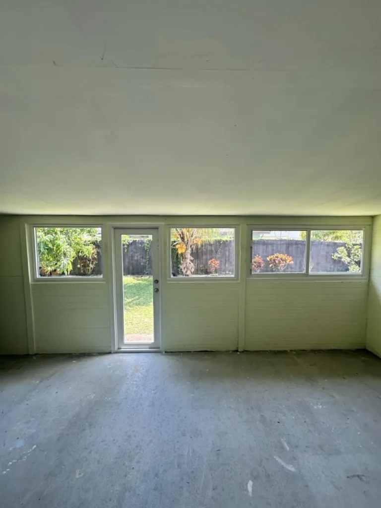 Empty room with new impact windows and a glass door across the back wall